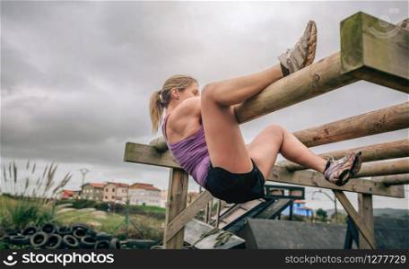 Female participant in a obstacle course doing weaver obstacle. Participant in a obstacle course doing weaver