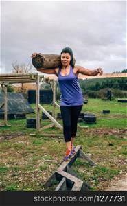 Female participant in an obstacle course carrying trunks outdoors. Sportswoman carrying trunks
