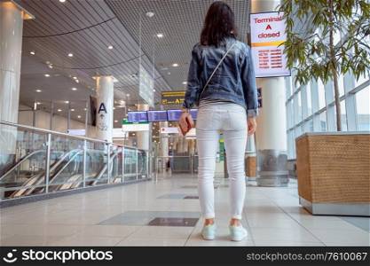 Female passenger at the airport looks at the Board about flight cancellations