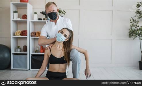 female patient doing exercises physiotherapy with physiotherapist with medical mask