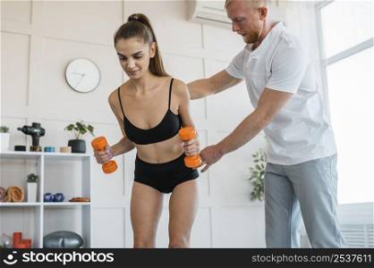 female patient doing exercises with dumbbells male physiotherapist