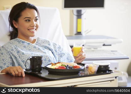 Female Patient Enjoying Meal In Hospital Bed