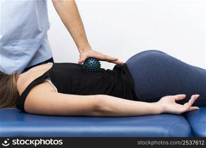 female patient getting massage from physiotherapist with ball