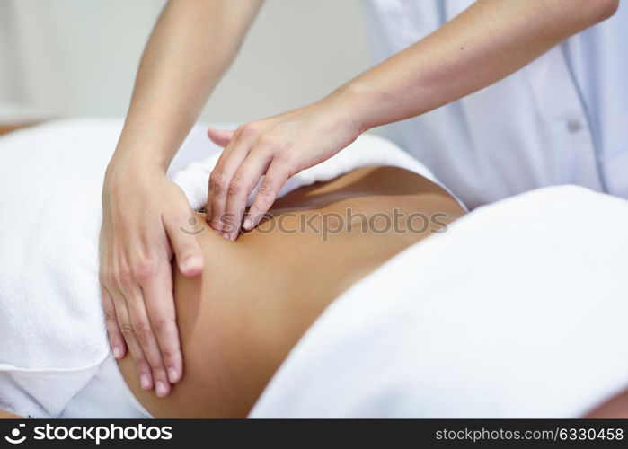 Female patient is receiving treatment by professional osteopathy therapist. Woman receiving a belly massage at spa salon