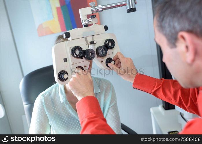 female patient looking through phoropter during eye exam