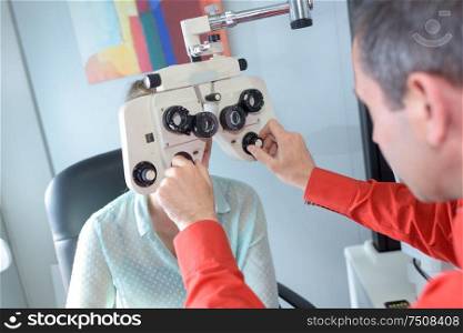female patient looking through phoropter during eye exam
