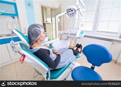 Female patient waiting for dental treatment in a dental chair. Dental Hygiene and Health conceptual image.