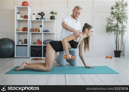 female patient with male physiotherapist dumbbell