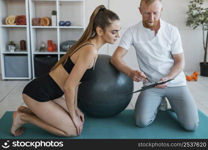 female patient with male physiotherapist looking clipboard