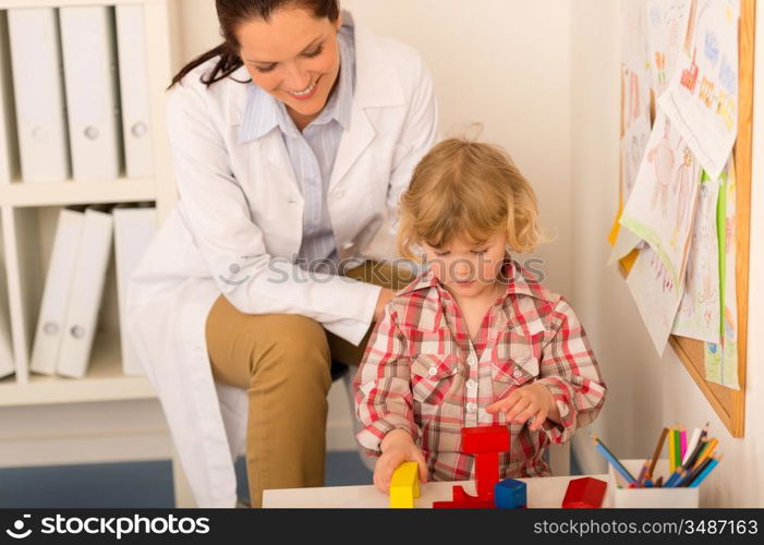 Female pediatrician playing with little girl at medical office