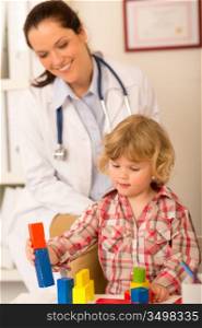 Female pediatrician playing with little girl at medical office