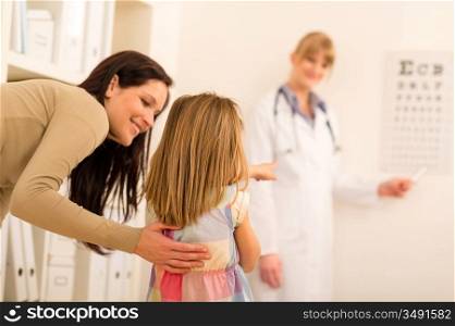 Female pediatrician pointing at eye chart mother and child visit