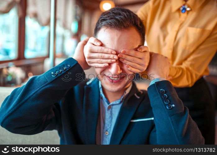 Female person closes eyes hands to man in restaurant. Romantic date of love couple