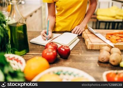 Female person cooking on the kitchen, healthy bio food. Vegetarian diet, fresh vegetables and fruits on wooden table. Female person cooking on the kitchen, bio food