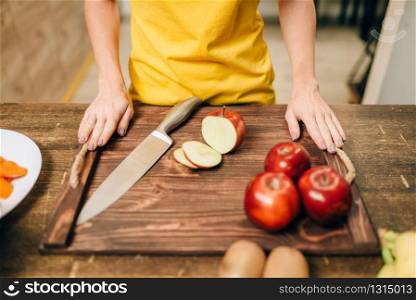 Female person cooking on the kitchen, healthy bio food preparing. Vegetarian diet, fresh vegetables and fruits on wooden table. Female person cooking, healthy bio food preparing