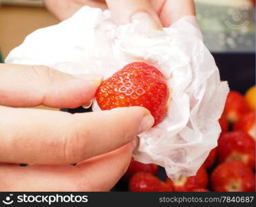 Female person drying up a washed strawberry with white household paper