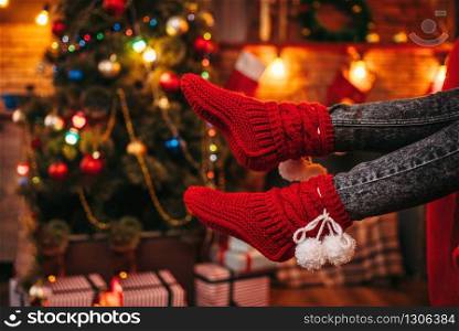 Female person feet in merry red socks, christmas tree with decoration on background, xmas holiday concept