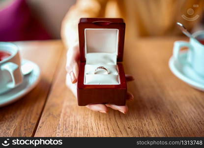 Female person hand holds box with golden wedding ring closeup view