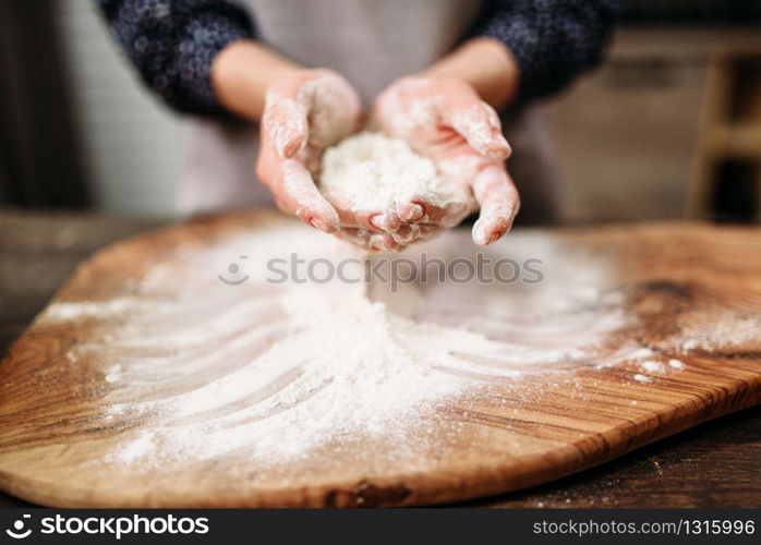 Female person hands holds dough in the flour over the cutting board. Cake cooking