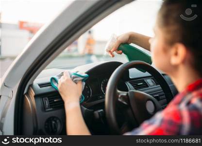 Female person polishes the dashboard of the car, polishing process on carwash. Lady on self-service automobile wash. Outdoor vehicle cleaning. Female person polishes the dashboard of the car