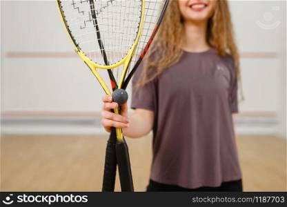 Female person shows squash racket and ball. Girl on game training, active sport hobby on court. Female person shows squash racket and ball