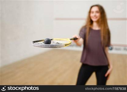 Female person shows squash racket and ball. Girl on game training, active sport hobby on court. Female person shows squash racket and ball