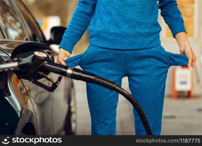 Female person with empty pockets on gas station, fuel filling. Petrol fueling, gasoline or diesel refuel service, high price on petroleum. Female person with empty pockets on gas station