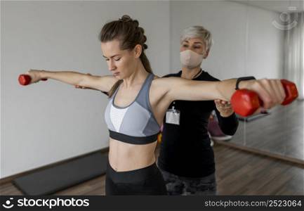 female personal trainer client using red dumbbell