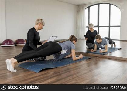 female personal trainer helping her client looking mirror