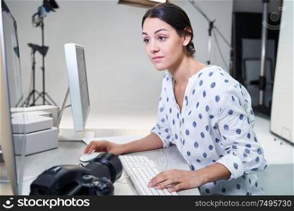 Female Photographer In Studio Reviewing Images From Photo Shoot On Computer