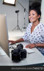 Female Photographer In Studio Reviewing Images From Photo Shoot On Computer