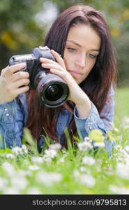 female photographer taking photo of flowering roses in summer day