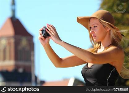Female photographer. taking pictures. Stylish autumn traveler woman in hat with camera outdoors in european city, old town Gdansk in the background, Poland Europe