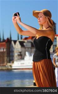 Female photographer. taking pictures. Stylish autumn traveler woman in hat with camera outdoors in european city, old town Gdansk in the background, Poland Europe