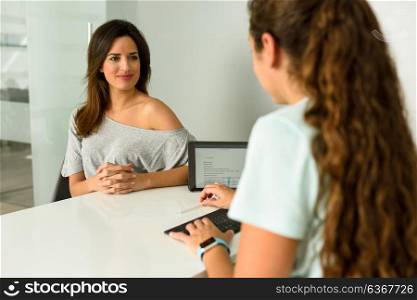 Female physiotherapist explaining diagnosis to her patient. Brunette woman having consultation with girl in medical office.