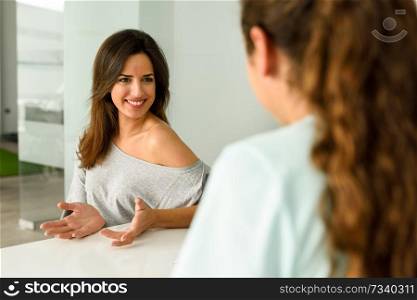 Female physiotherapist explaining diagnosis to her patient. Brunette woman having consultation with girl in medical office.. Female physiotherapist explaining diagnosis to her woman patient. 