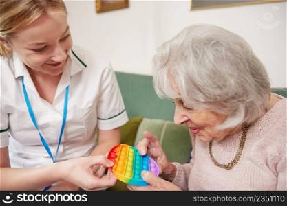 Female Physiotherapist Getting Senior Woman To Use Fidget Toy