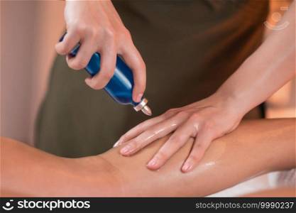 Female physiotherapist holding a bottle with massage oil 