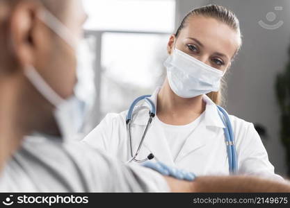 female physiotherapist with medical mask examining man