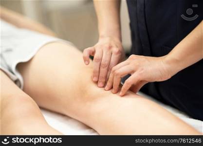 Female Physiotherapist woman doing a treatment on a young woman&rsquo;s knee.. Physiotherapist woman doing a treatment on a woman&rsquo;s knee.