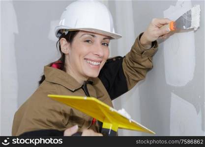female plasterer painter doing a wall renovation