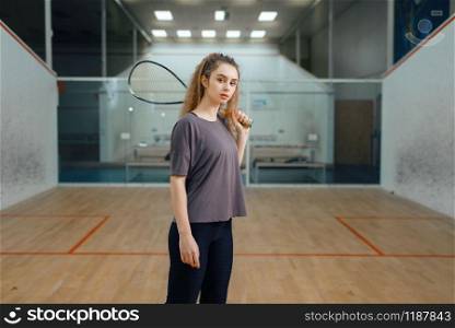 Female player poses with squash racket on court. Girl on game training, active sport hobby, fit workout for healthy lifestyle. Female player poses with squash racket on court