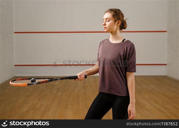Female player with squash racket and ball on court. Girl on game training, active sport hobby, fit workout for healthy lifestyle. Female player with squash racket and ball on court