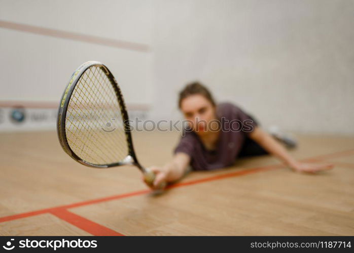 Female player with squash racket lies on the floor. Girl on game training, active sport hobby on court. Female player with squash racket lies on the floor