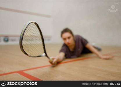 Female player with squash racket lies on the floor. Girl on game training, active sport hobby on court. Female player with squash racket lies on the floor