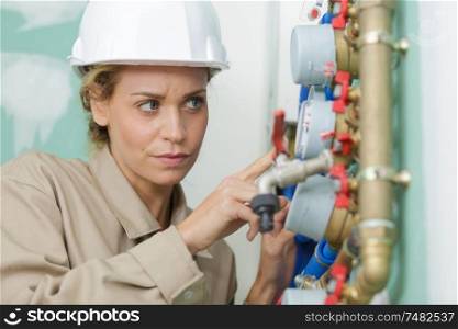 female plumber fixing water meter with adjustable wrench