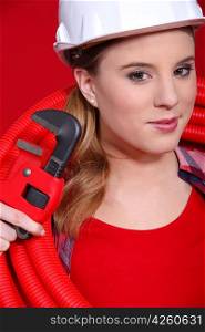 Female plumber in red with a red pipe and wrench