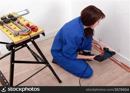 Female plumber installing hot and cold water pipes