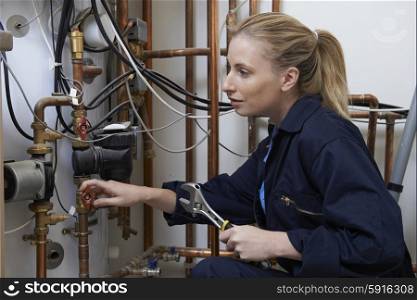 Female Plumber Working On Central Heating Boiler