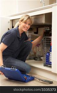 Female Plumber Working On Sink In Kitchen
